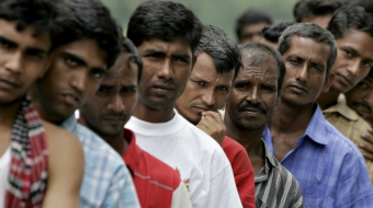 Bangladeshi migrant workers wait in line for food donated by a goodwill charity group for Christmas outside the Bangladeshi High Commission in Kuala Lumpur, 25 December 2007. At least 225 hundred Bangladeshi migrant workers have been forced to camp in their country's mission in Malaysia after they ran away from their employer for alleged abuse. The Bangladesh high commission has turned a section of its mission into a temporary shelter for the workers who are living in unhealthy conditions and little food to eat since early December. AFP PHOTO/TENGKU BAHAR (Photo by TENGKU BAHAR / AFP)