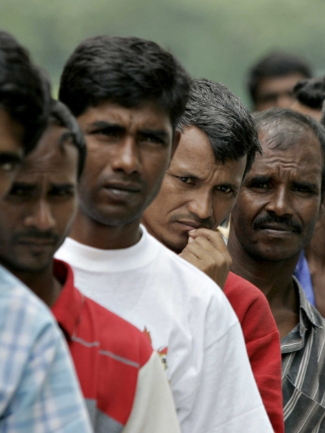 Bangladeshi migrant workers wait in line for food donated by a goodwill charity group for Christmas outside the Bangladeshi High Commission in Kuala Lumpur, 25 December 2007. At least 225 hundred Bangladeshi migrant workers have been forced to camp in their country's mission in Malaysia after they ran away from their employer for alleged abuse. The Bangladesh high commission has turned a section of its mission into a temporary shelter for the workers who are living in unhealthy conditions and little food to eat since early December. AFP PHOTO/TENGKU BAHAR (Photo by TENGKU BAHAR / AFP)
