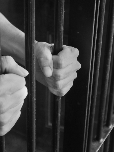 Prison Cell Bars.Hand of the prisoner holding steel lattice jail bars.Criminal justice imprisonment concept.